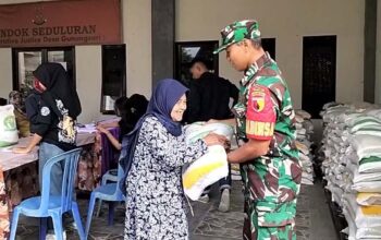 Babinsa Gunungsari membantu warga menerima bantuan beras dari Bulog.