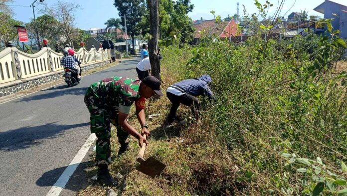 Babinsa Pandanrejo, Serda Bambang Setiono, bersama warga dan perangkat desa membersihkan TPU Dusun Pandan.