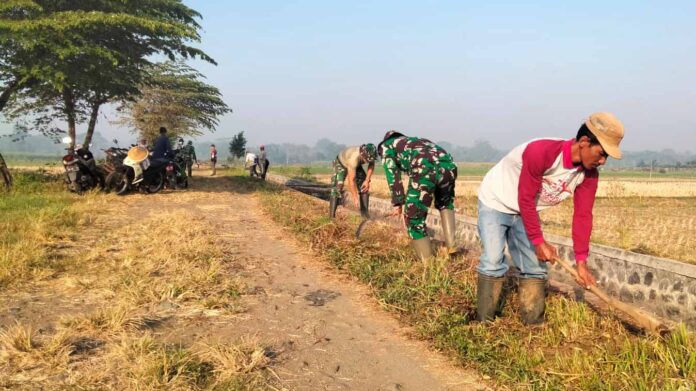 Anggota TNI dari Koramil 0818/35 Pagelaran bersama warga Desa Kademangan membersihkan gorong-gorong.