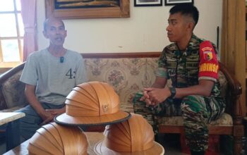 Serda Deni Akbar, Babinsa Koramil Kepanjen, mendampingi Bapak Kokoh, pengrajin topi polka dari kulit kayu jati, di workshopnya di Desa Tegalsari, Malang.