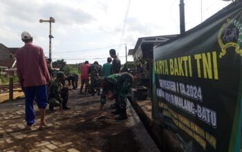 Gotong royong TNI dan warga Desa Sumberpucung dalam kegiatan Karya Bakti pemasangan paving