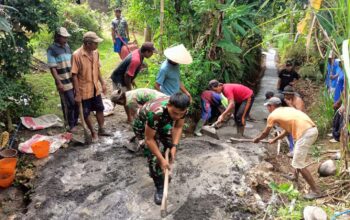 Babinsa Bantur Serka Hadi Sunarko membantu warga Dusun Durmo dalam kegiatan kerja bakti pengecoran jalan