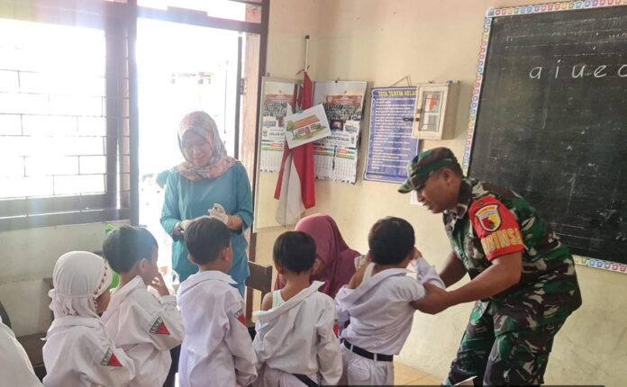 Babinsa Kepanjen Serda Abd. Faruk mendampingi kegiatan imunisasi anak di SD Negeri 1 Kepanjen