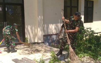 Anggota Koramil Junrejo dan masyarakat bekerja sama dalam kegiatan pembersihan di Balai RT Dadaptulis