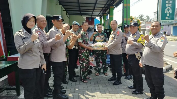 Kapolsek Ngajum dan anggota TNI merayakan HUT TNI ke-79 dengan tumpeng dan kehadiran masyarakat serta instansi lokal.